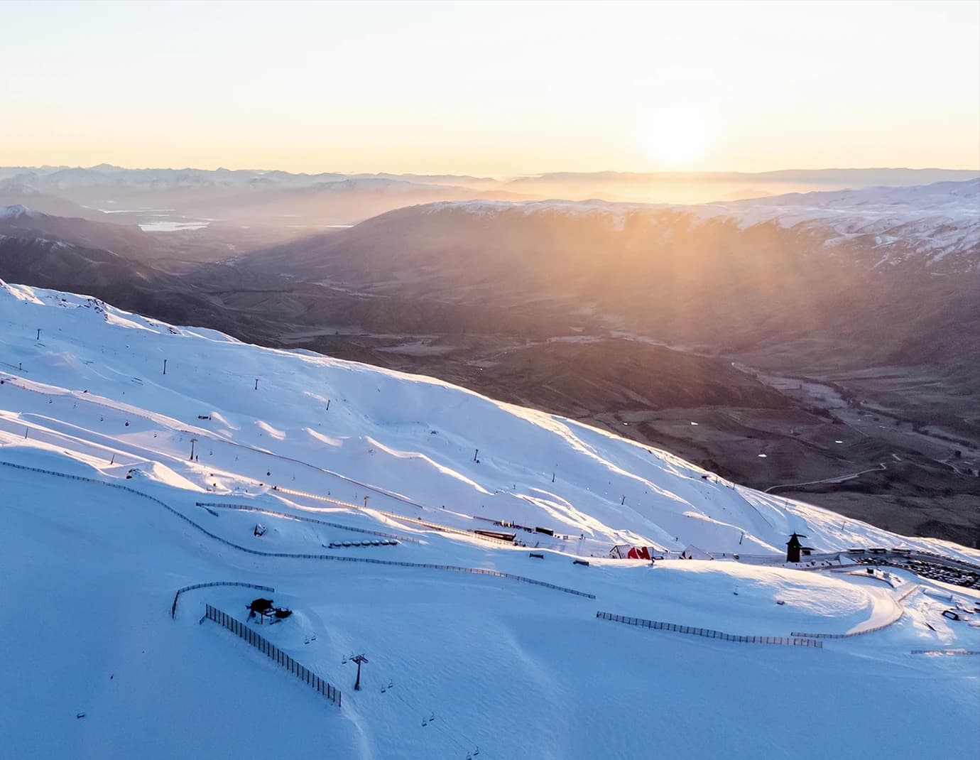 An aerial view of Cardrona Alpine Resort at sunrise. Showcases base and park from above.