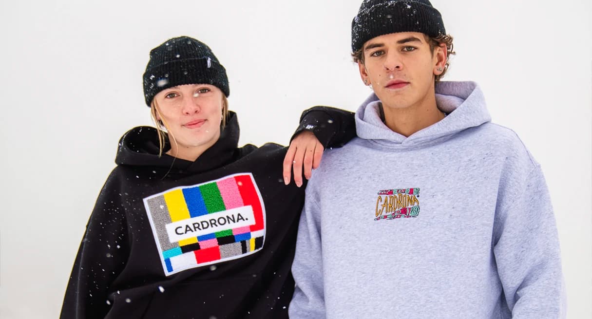 Two models wear Cardrona-themed hoodies in the snow.