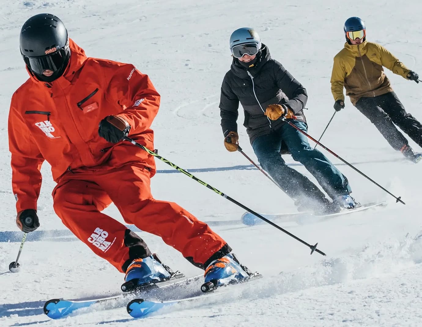 Three skiers, including an instructor, skiing in a line down a slope.