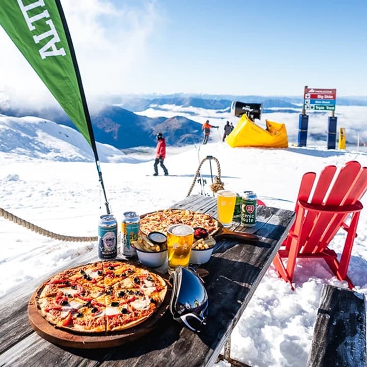 A picnic table with beers and pizza at the Altitude bar, Treble Cone.