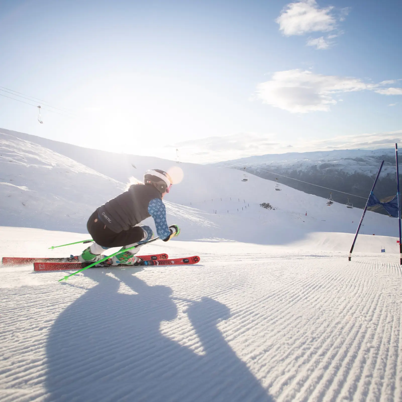 Skier training through gates on a sunny alpine slope.