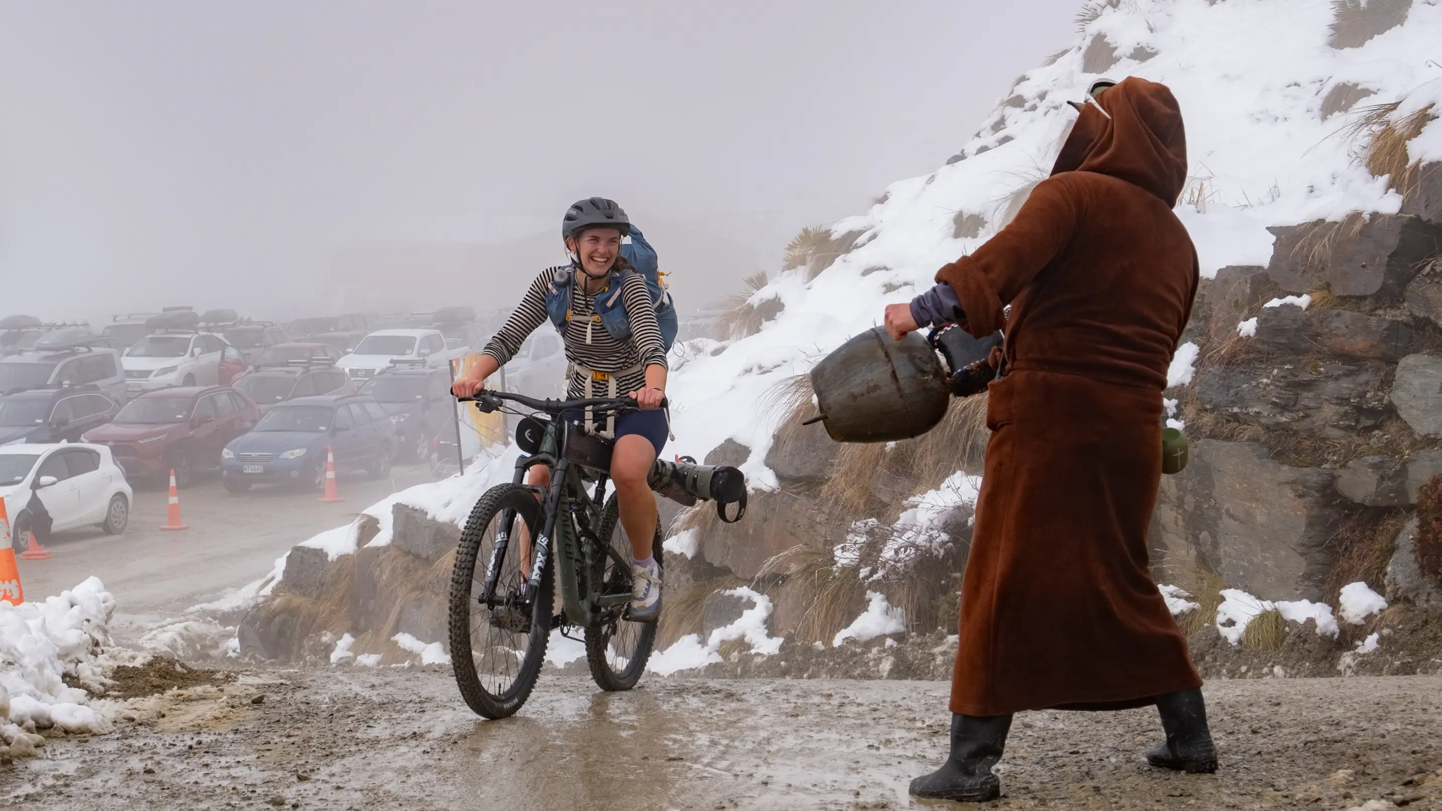 Women smiling on a bike while riding up a snowy mountain.