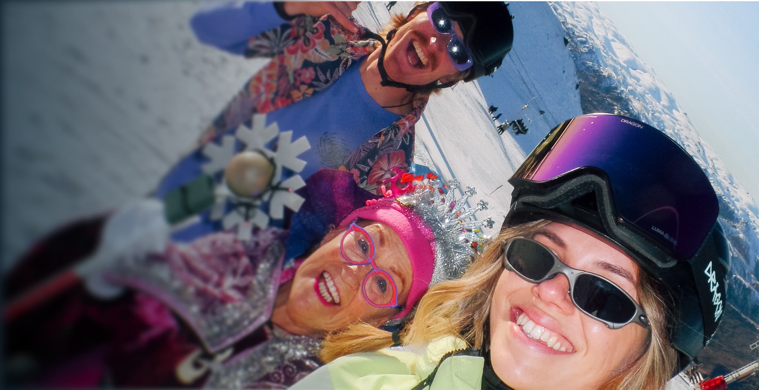 A group of skiers take an excited selfie on a sunny day on the mountain.