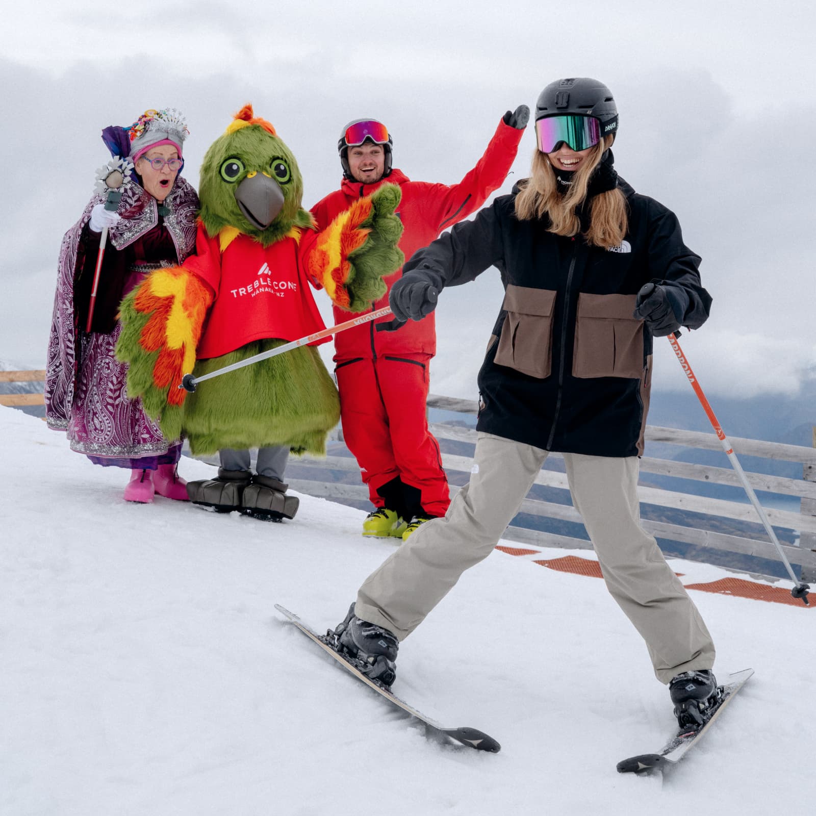 A skier takes part in a ski lesson with their instructor, a kea mascot and fairy god mother encourzging them in the background.