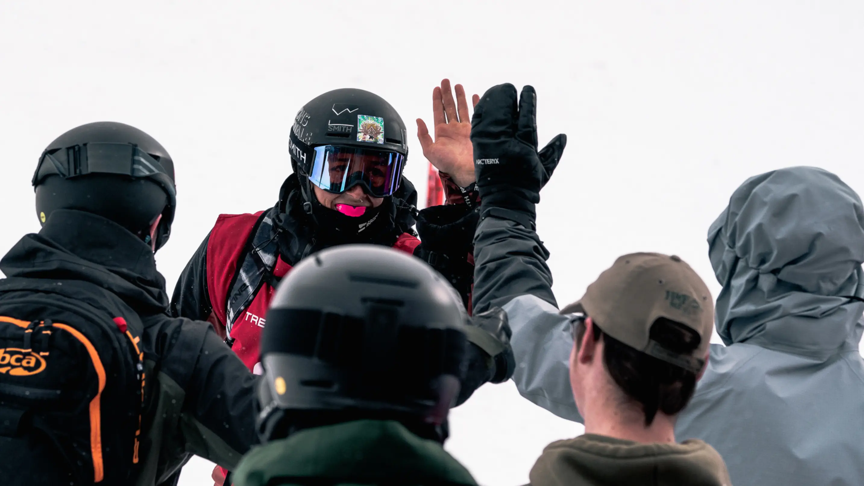 Freeride skier in a Smith helmet and goggles high-fiving supporters after a competition run.