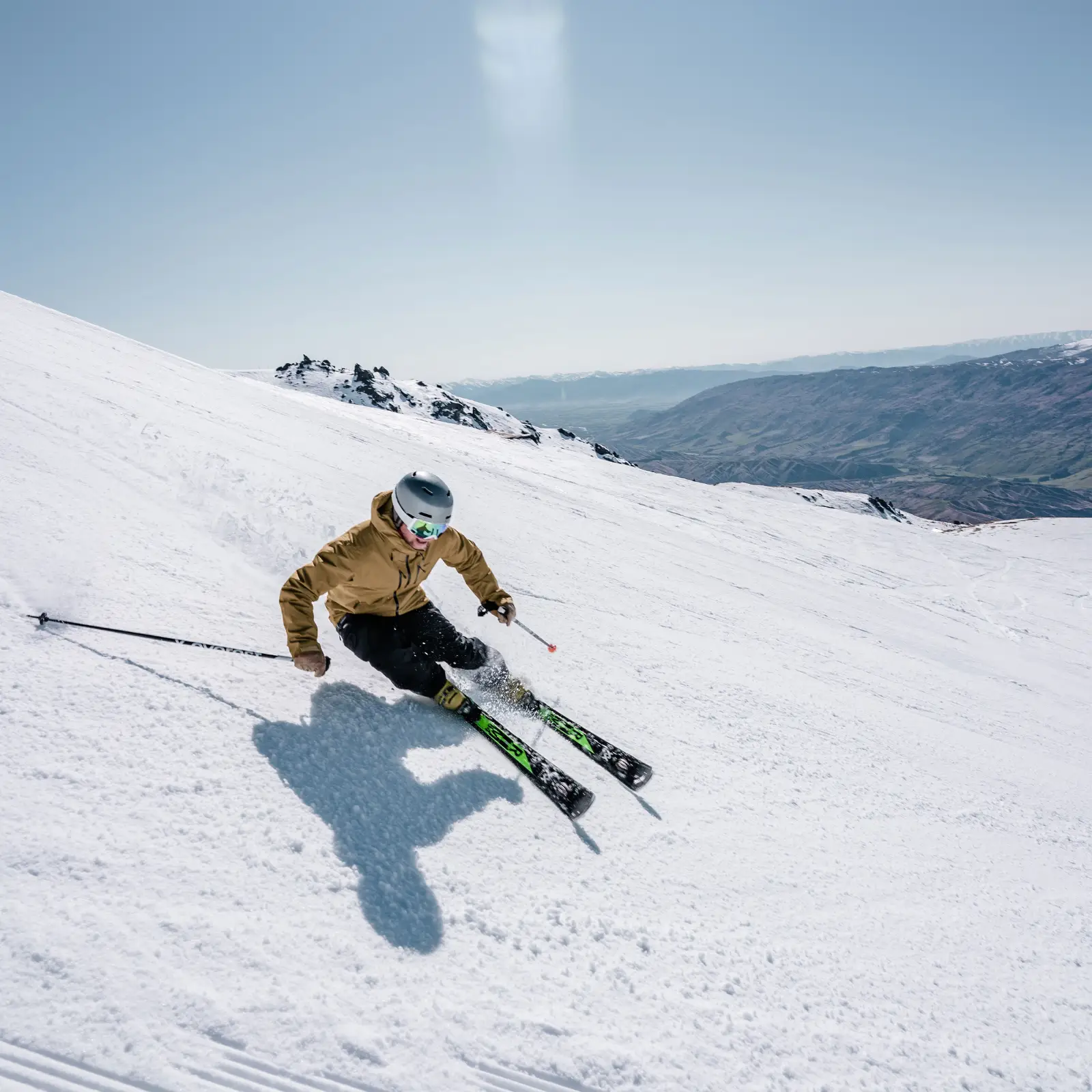 Skier carves down a snowy mountain on a bluebird day.