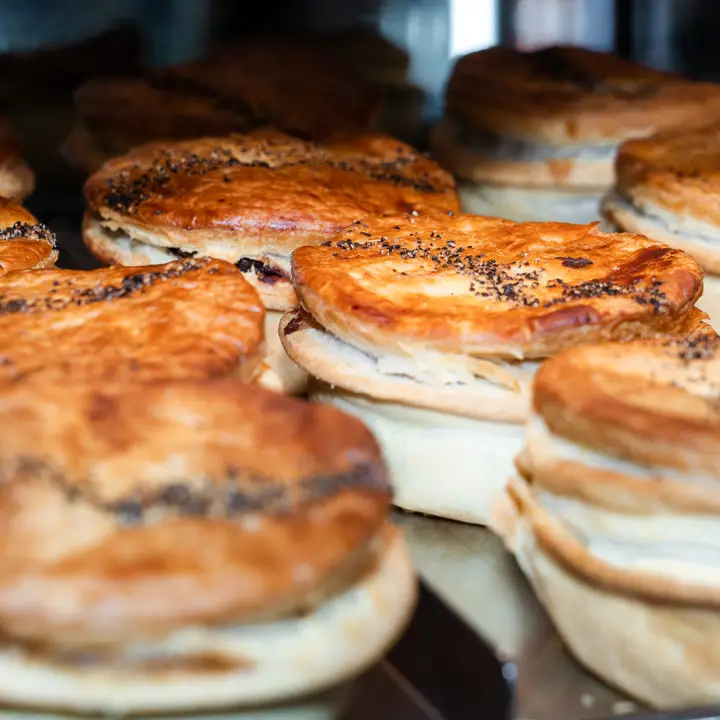 Close up of hot meat pies lined up in a café.