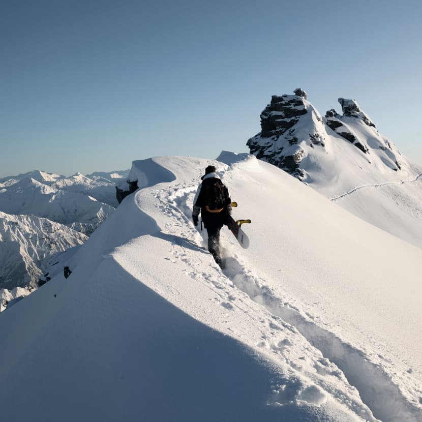 A skier hiking to the summit of Treble Cone on a blue skies powder day.