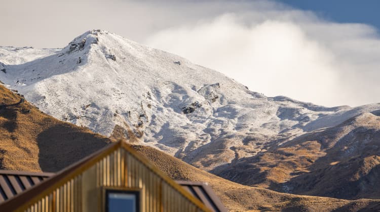 Snow-dusted mountain peaks rising behind Mt Cardrona Station.