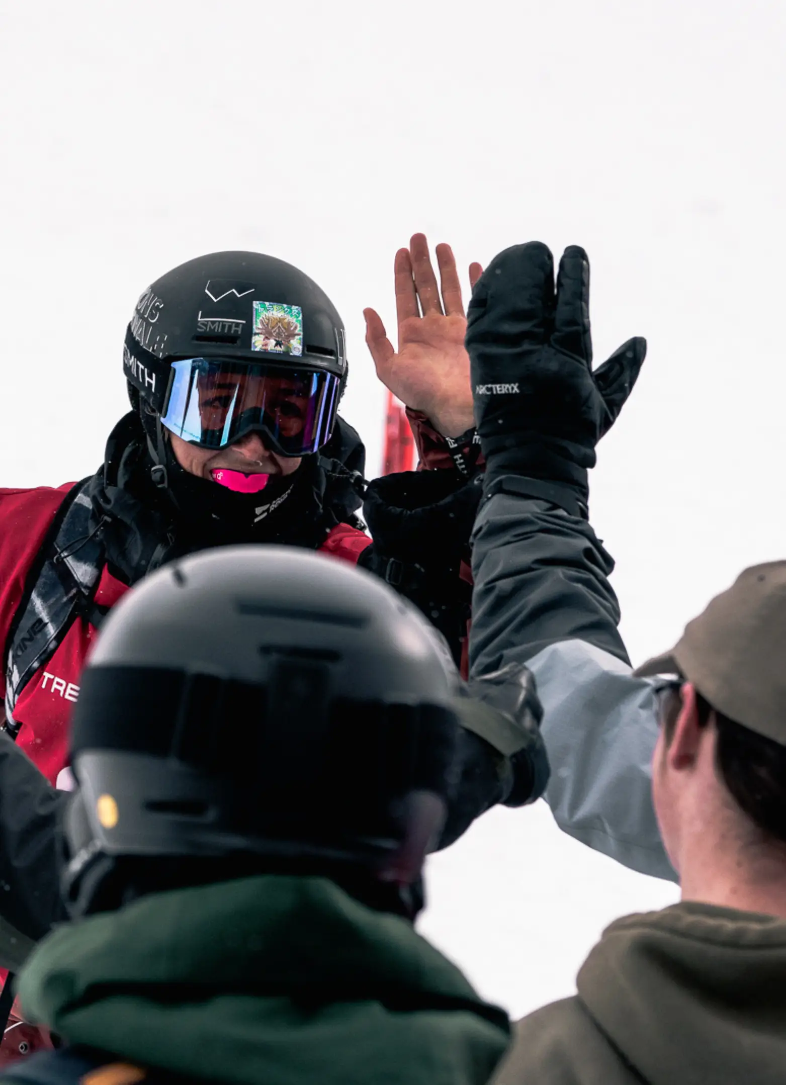 Freeride skier in a Smith helmet and goggles high-fiving supporters after a competition run.