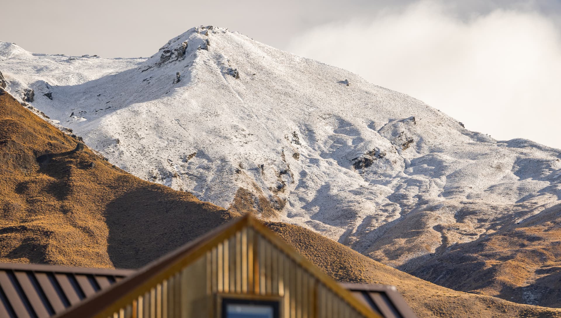 Snow-dusted mountain peaks rising behind Mt Cardrona Station.
