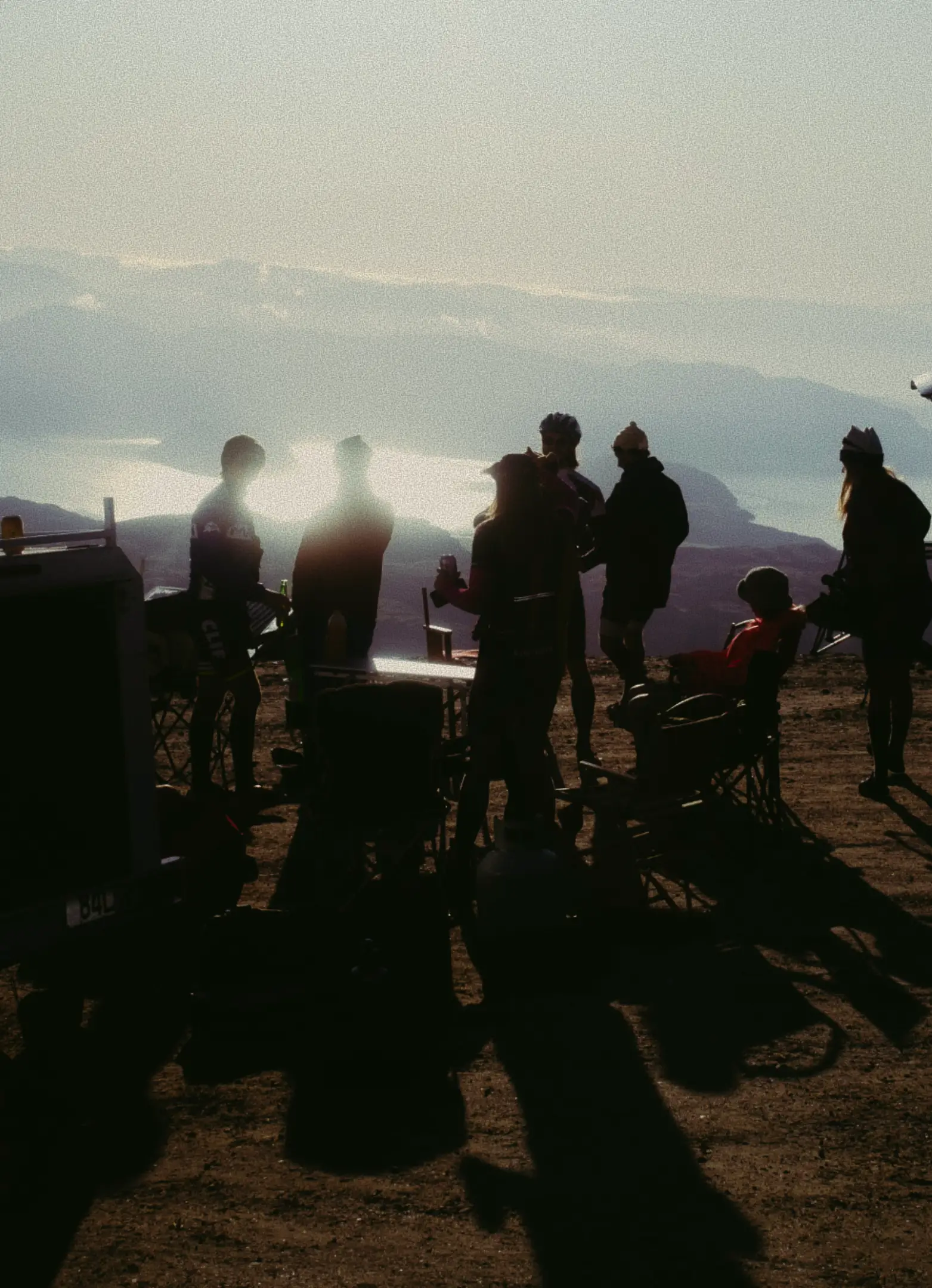 Group of people standing in the car park at the top of ski field at sunrise.