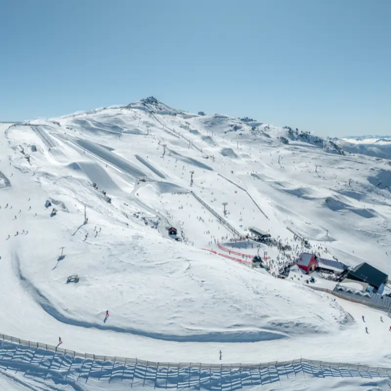 Drone shot of Cardrona Alpine Resort's main basin and base area in fresh snow on a bluebird day.